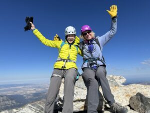 Two women on the summit of the Grand Teton with arms raised high.